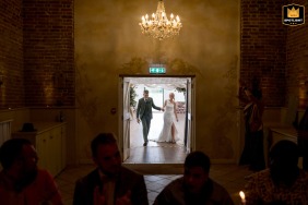 A bride and groom enter their wedding breakfast at Elms Barn in Norfolk, UK. The image shows the couple as they are announced into the reception.